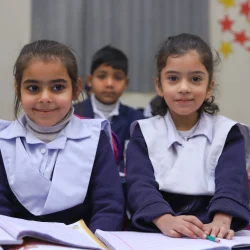 Smiling school girls with notebooks in a vibrant classroom at NARA School.