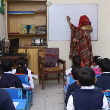 Teacher giving a whiteboard lesson to attentive students in a classroom.