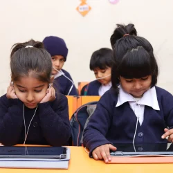 Young learners using headphones and tablets for interactive education.