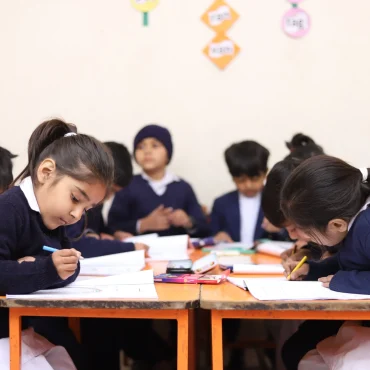 Children concentrating on their classwork, writing in notebooks.