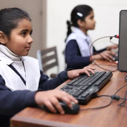 Young girls learning the use of technology in a computer lab.